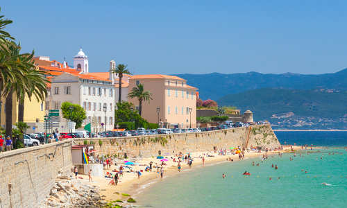 Ajaccio, Corsica coastal cityscape with blue azure waters and mountain background