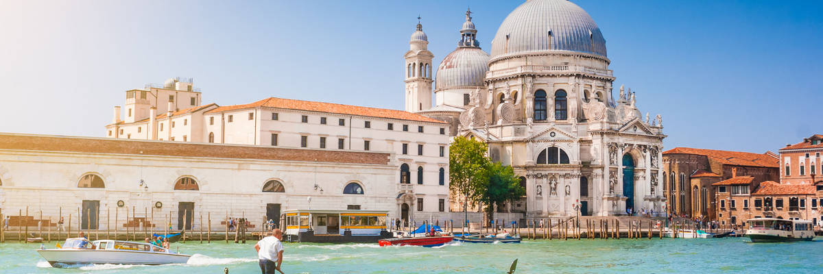 Beautiful view of traditional Gondola on Canal Grande with historic Basilica di Santa Maria della Salute in the background on a sunny day in Venice, Italy
