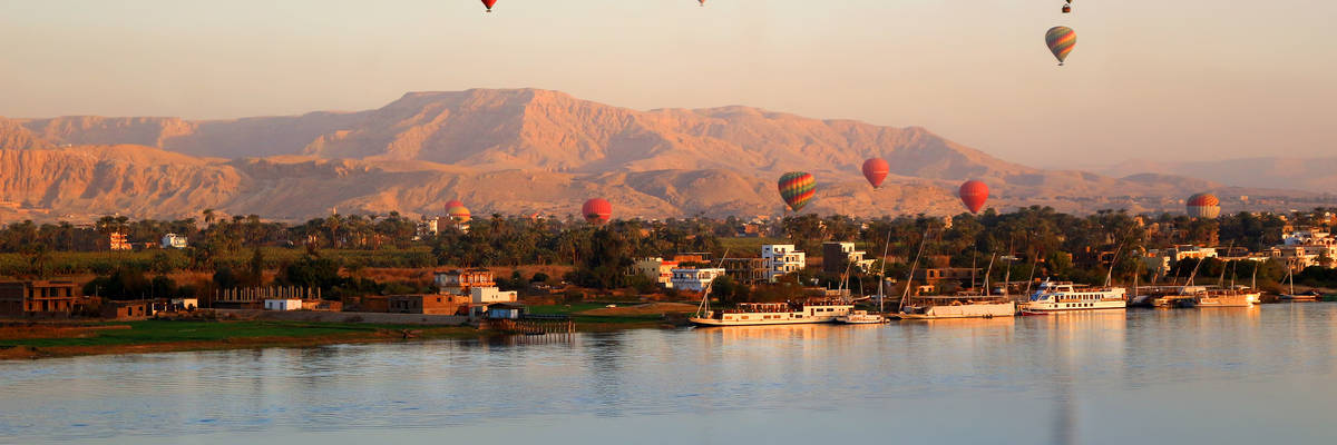 Many Hot air balloons floating over the Nile River in Luxor at sunrise