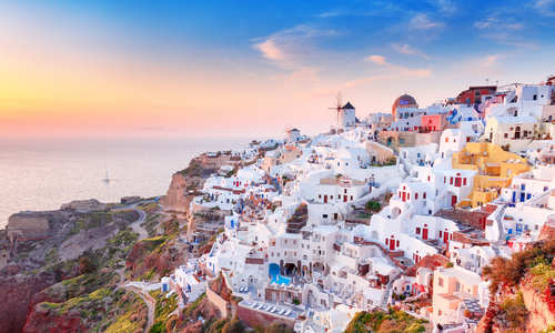 sunset over whitewashed houses overlooking the sea.